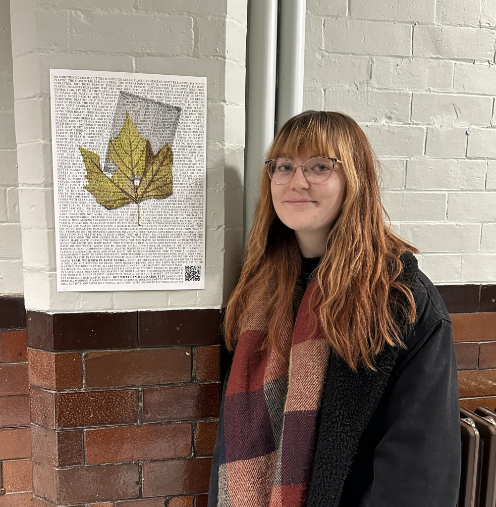 Person standing next to a poster displayed on a wall.