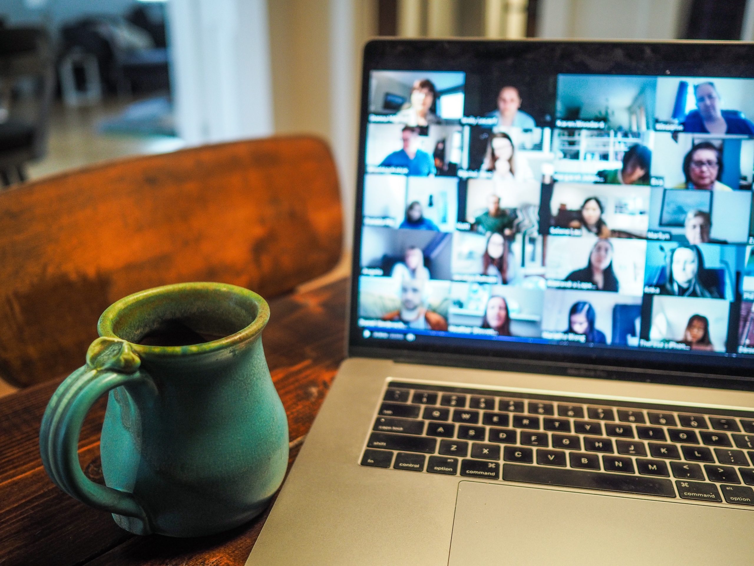 A laptop sitting on a table with a zoom meeting taking place on the screen