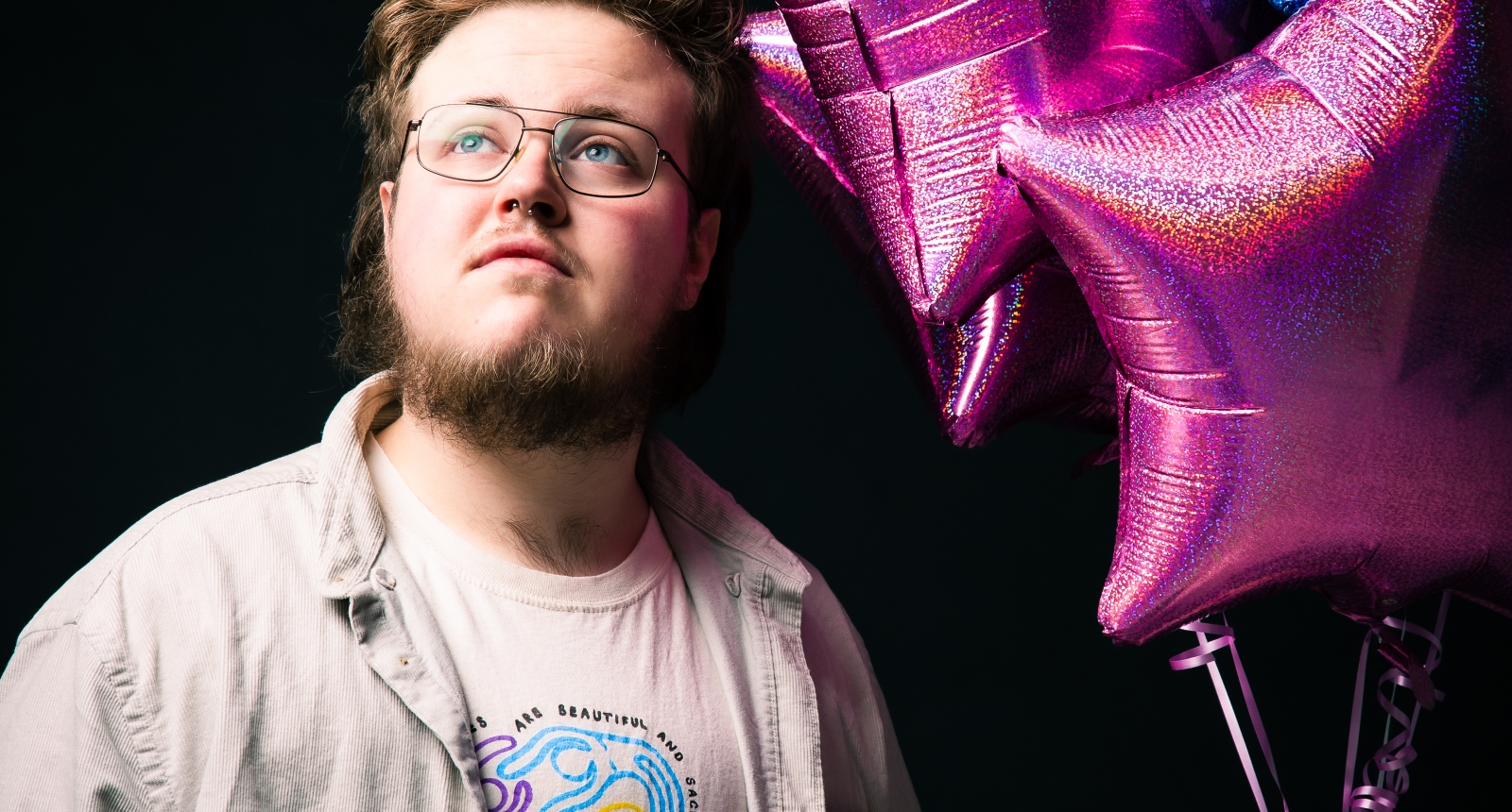 Ben Hodge holding a display of pink and blue balloons, the colours of the Trans flag