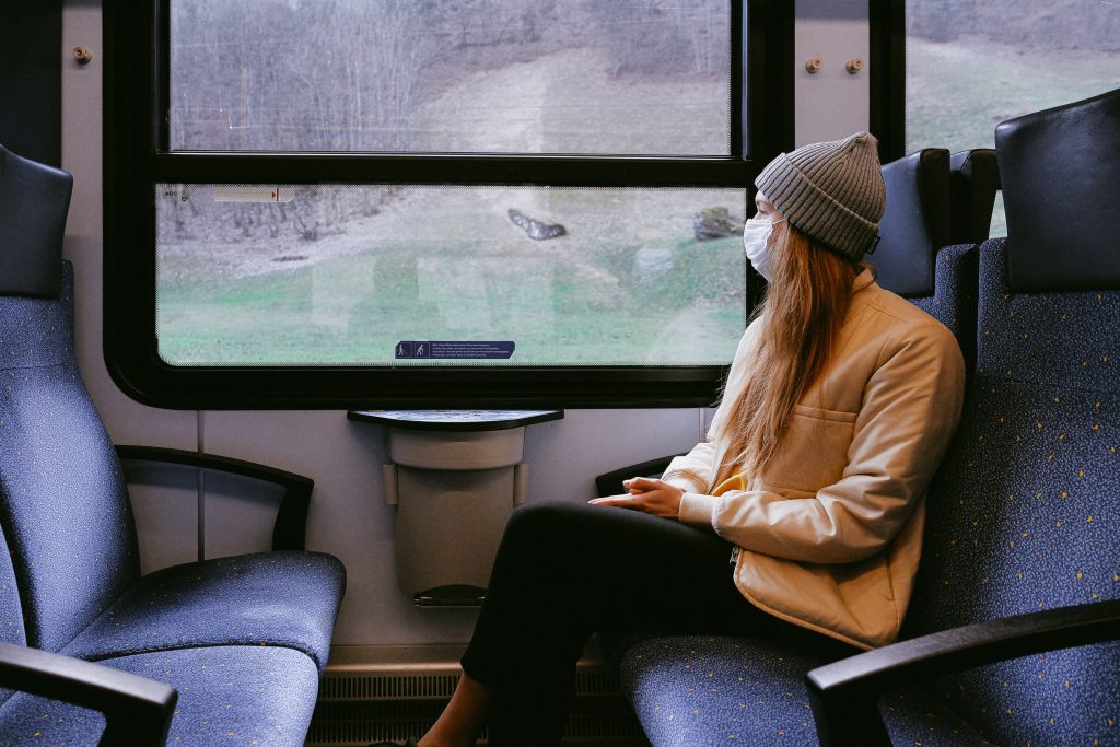 a woman with long hair sits in a train carriage looking out of the window