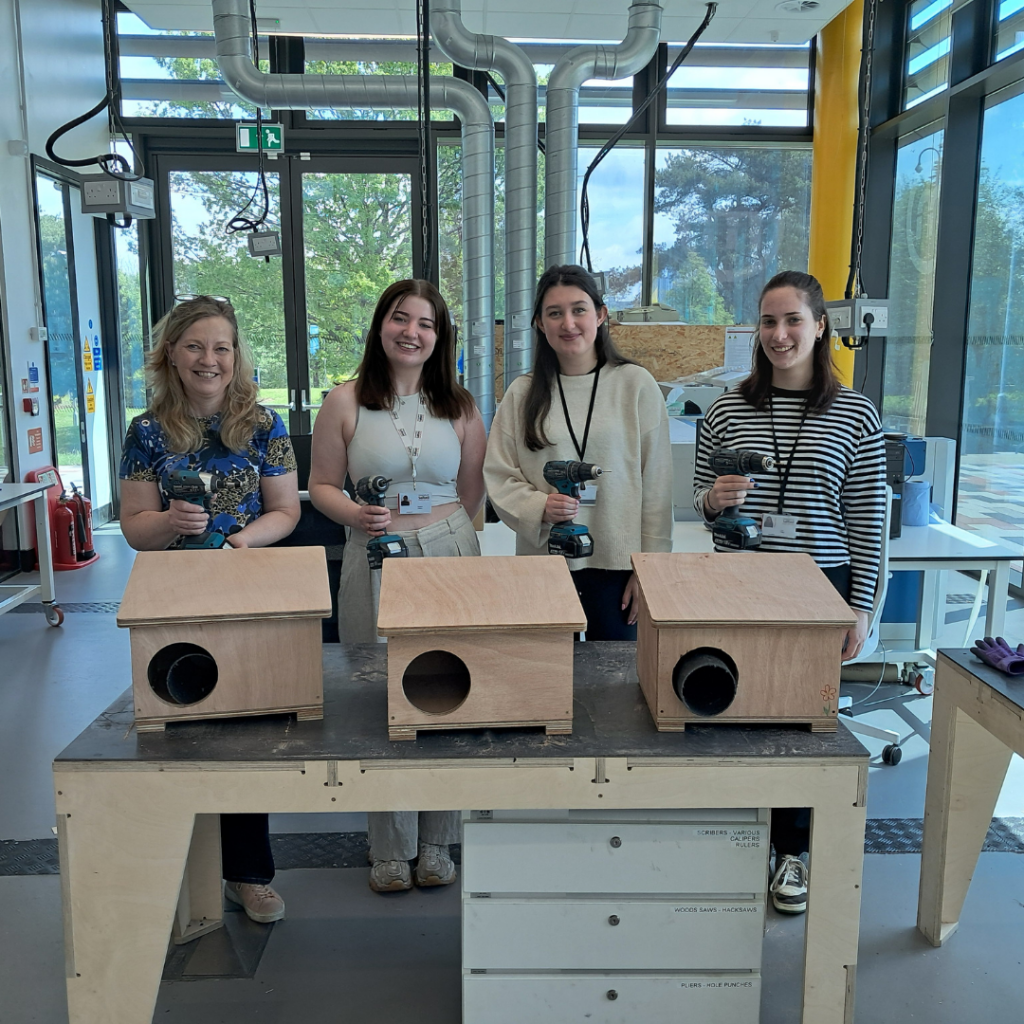 Four people stood with Hedgehog Houses