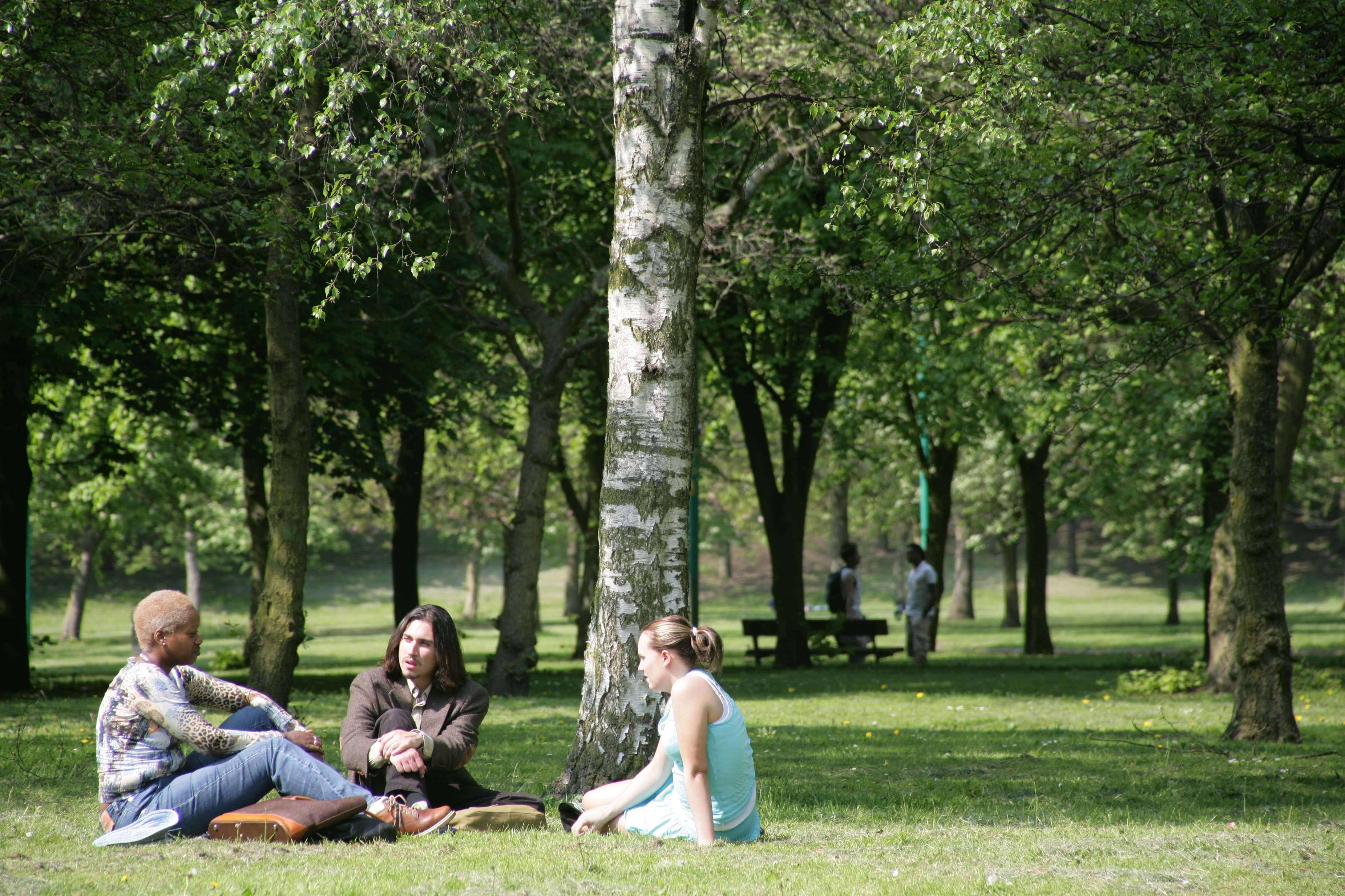 Students sitting within Peel Park, Salford