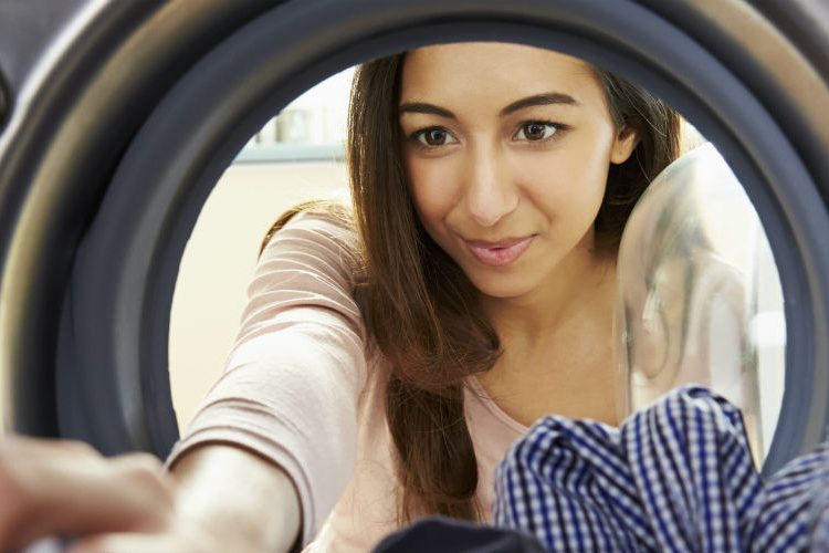 Woman loads washing into a washing machine