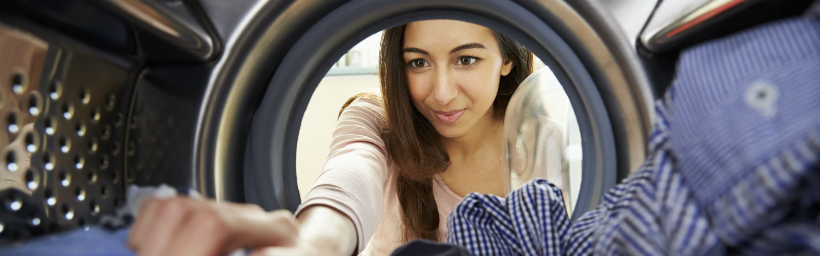 Woman loads washing into a washing machine