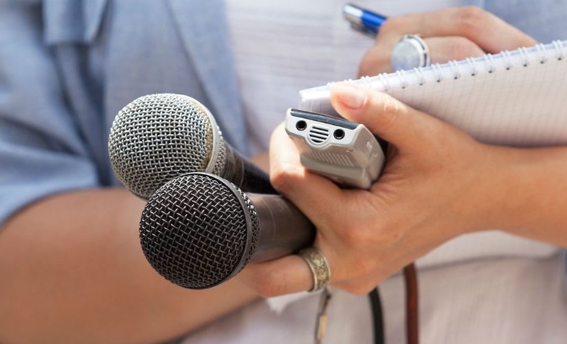 Journalist holding microphones and notepad