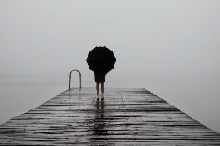 A girl with an umbrella looking at the water