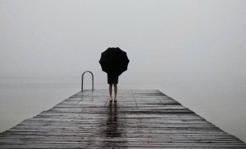 A girl with an umbrella looking at the water