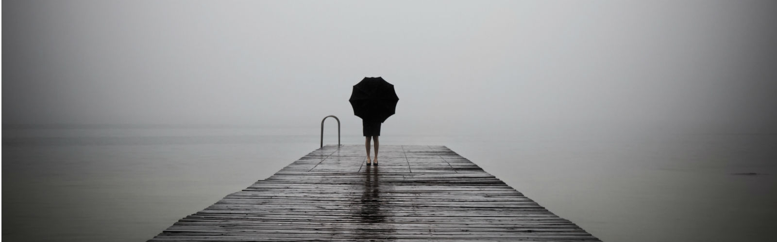 A girl with an umbrella looking at the water