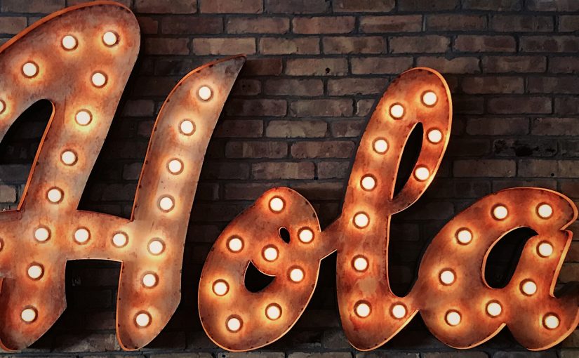 the word 'Hola' in lights on a brick wall