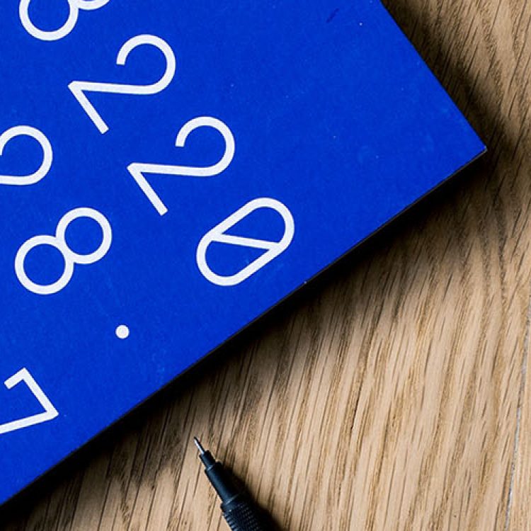 An up close shot of a laptop and a blue notebook