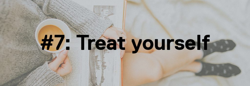 Photo by Anthony Tran on Unsplash. In the background image is a girl in a grey jumper and dark blue socks with a book on her lap whilst in one hand she carries a cup of tea. The foreground text says '#7: Treat Yourself'