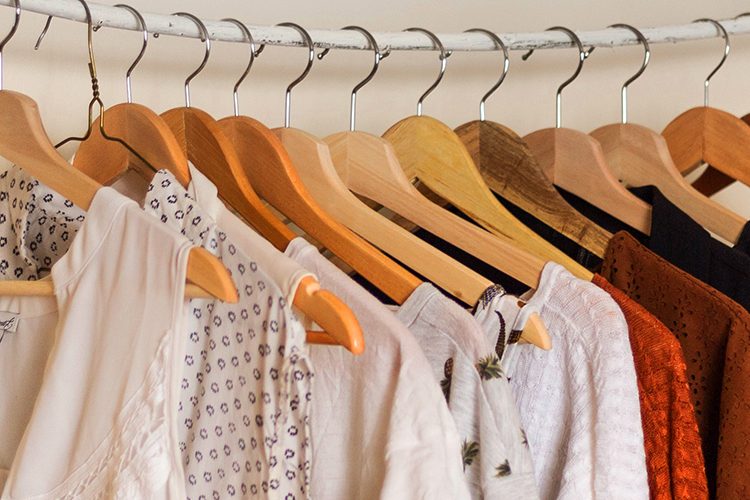 Several pieces of clothing are hung with clothes hangers on a rail