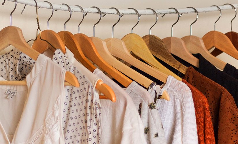 Several pieces of clothing are hung with clothes hangers on a rail