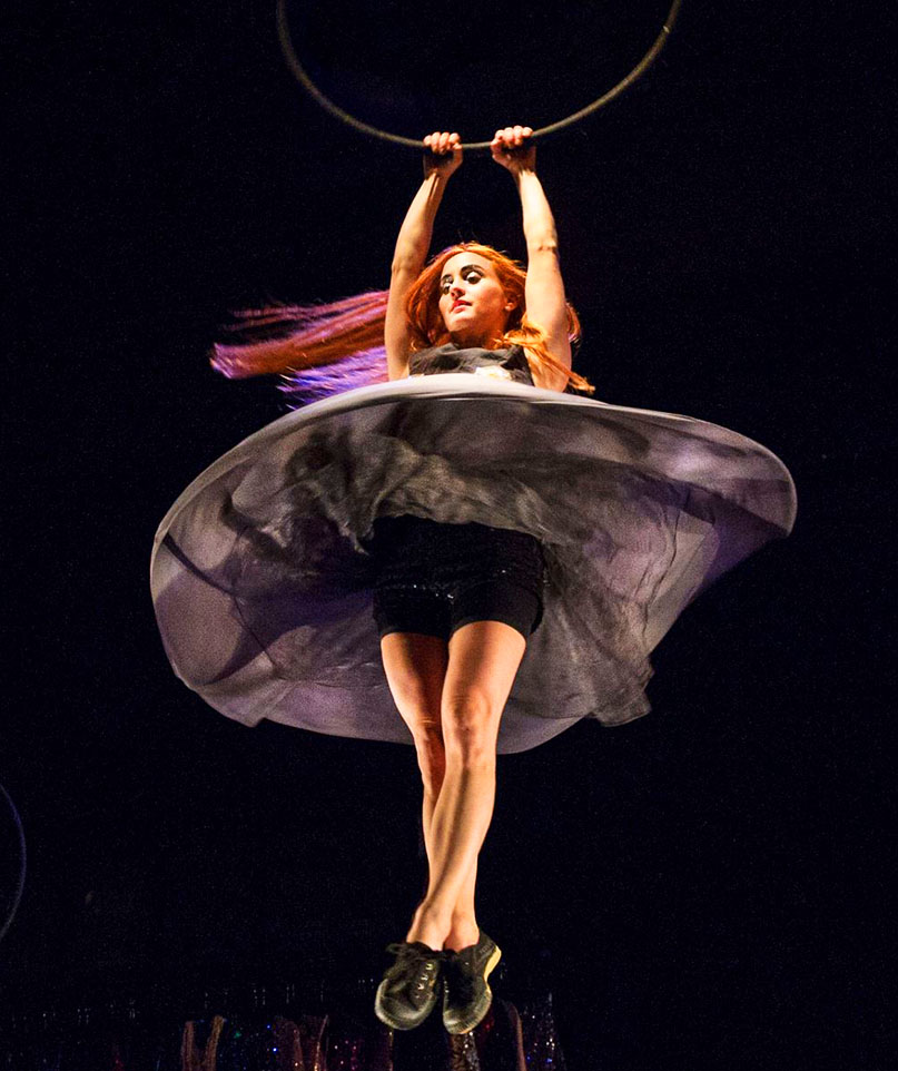 In the air, Sandy holds on to the bottom of a hoop as she spins round and round, making her dress flow upwards like a disc. 