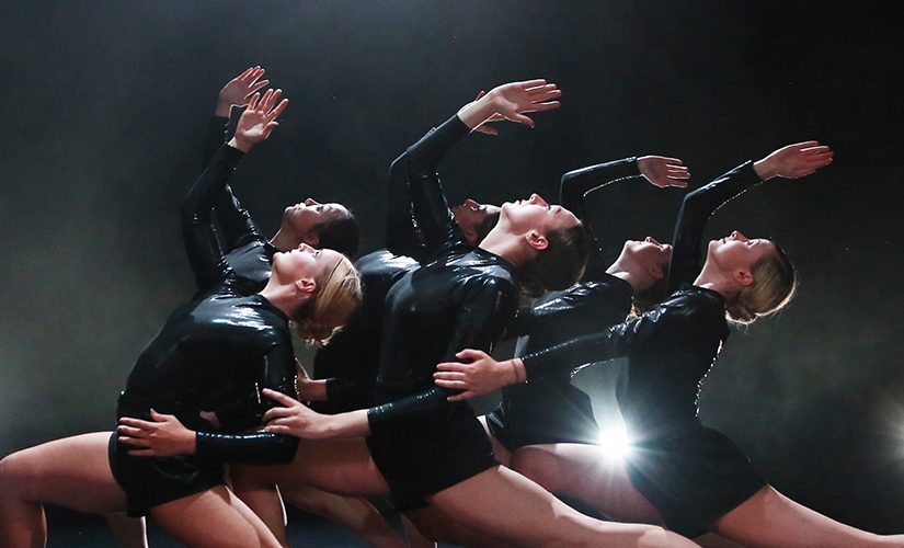 The ensemble of 'Emergence 19/20' performing on stage in black leotards