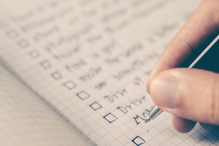 Photo of a hand writing down a checklist in a notebook