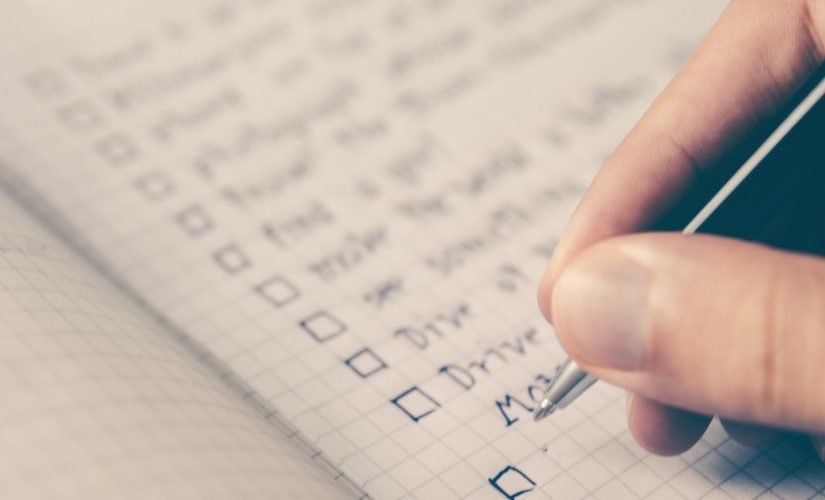 Photo of a hand writing down a checklist in a notebook