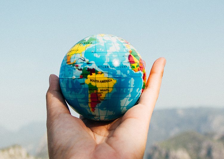 Photo of a person's hand holding a small globe