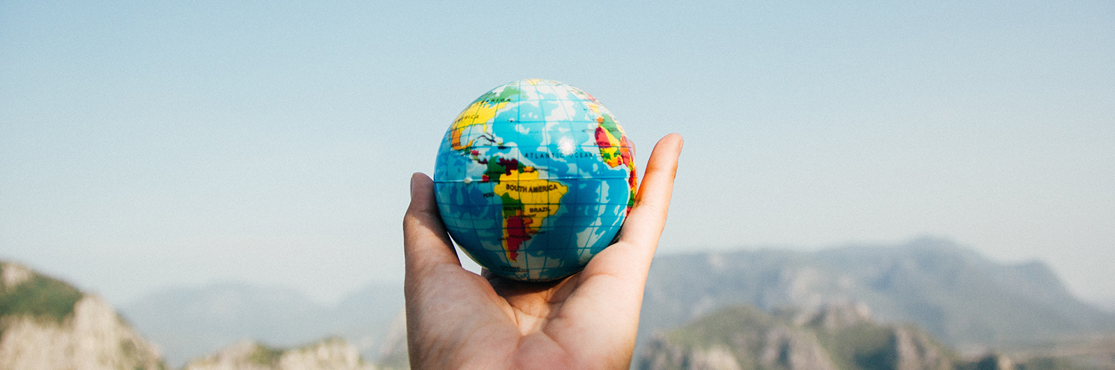 Photo of a person's hand holding a small globe