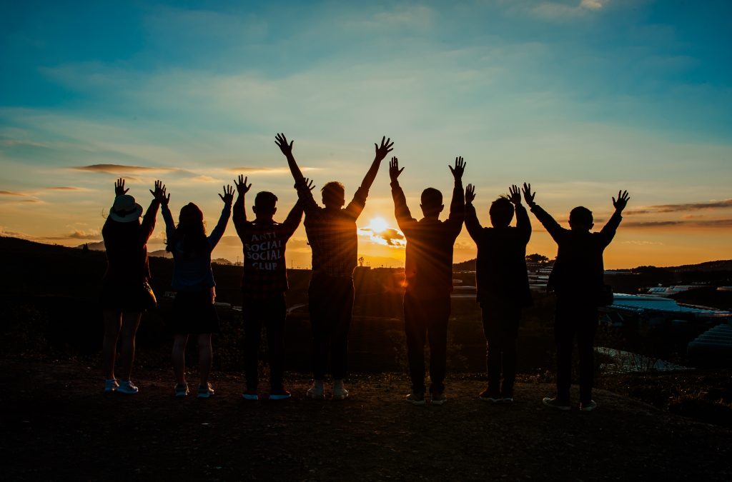 silhouette photo of group of people raising their hand