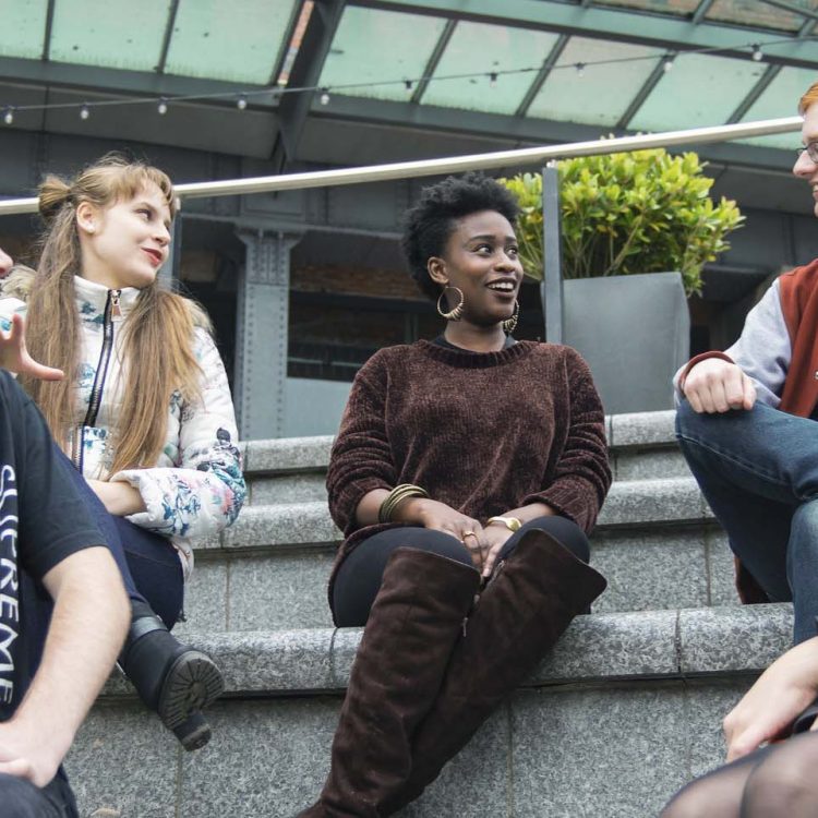 Photo of different students sitting and talking to each other