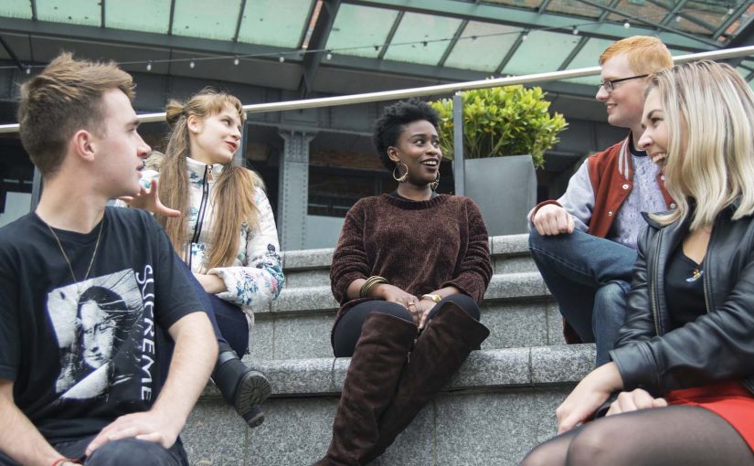 Photo of different students sitting and talking to each other