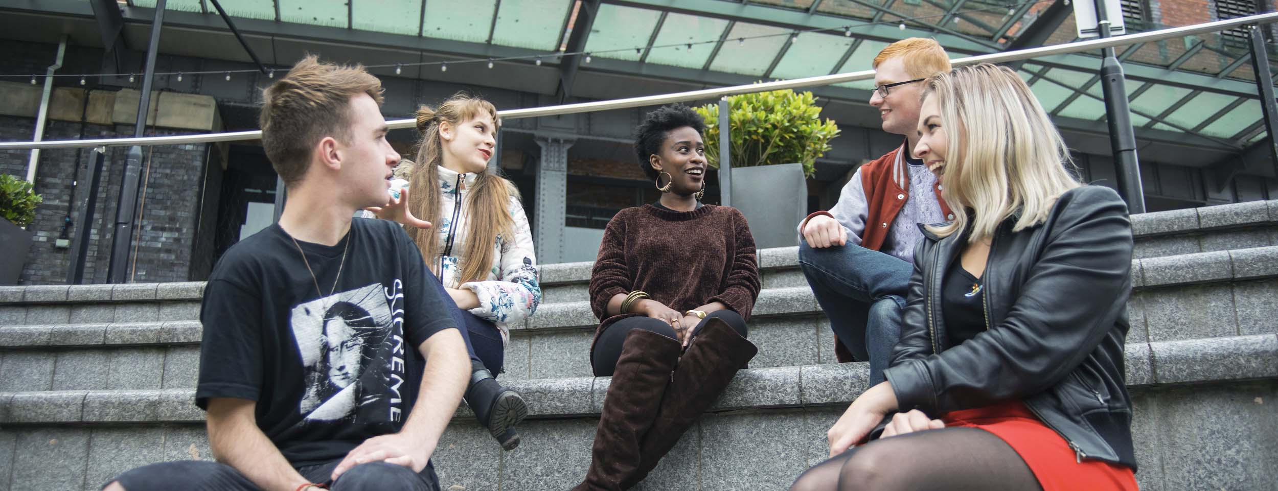 Photo of different students sitting and talking to each other