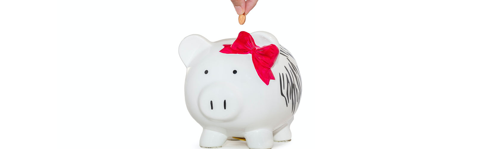 Photo of a hand putting a coin into a white piggy bank