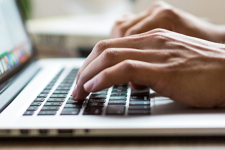 Photo of a person typing on the laptop