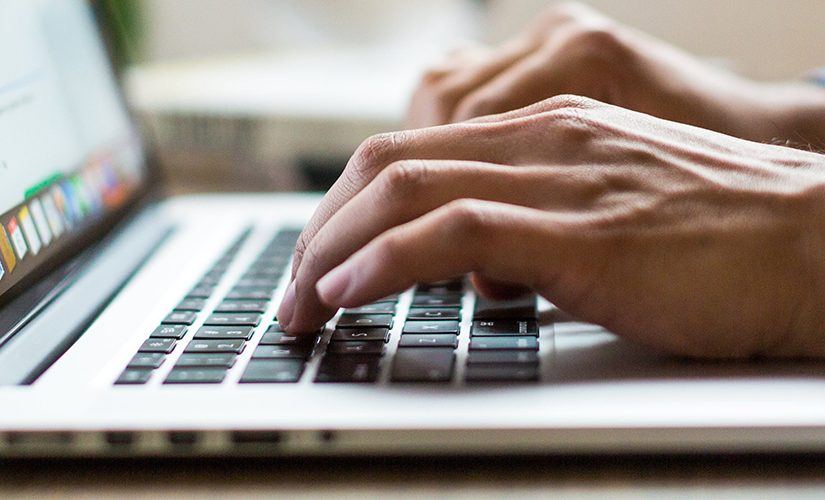 Photo of a person typing on the laptop