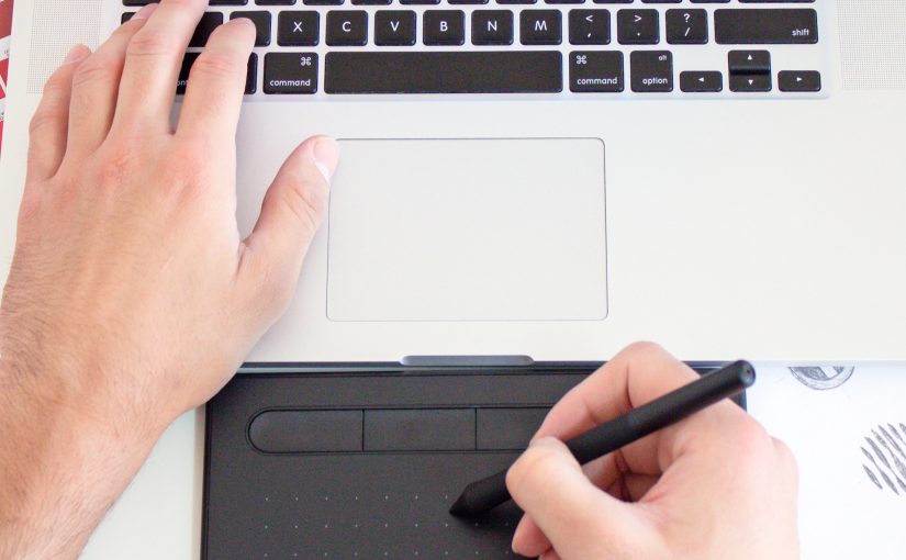 Photo of left handing typing on a macbook and right hand drawing using a digital pen