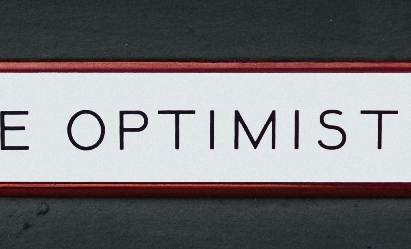 Photo of text "Be Optimistic" written in Black Capital Letters in a White Background