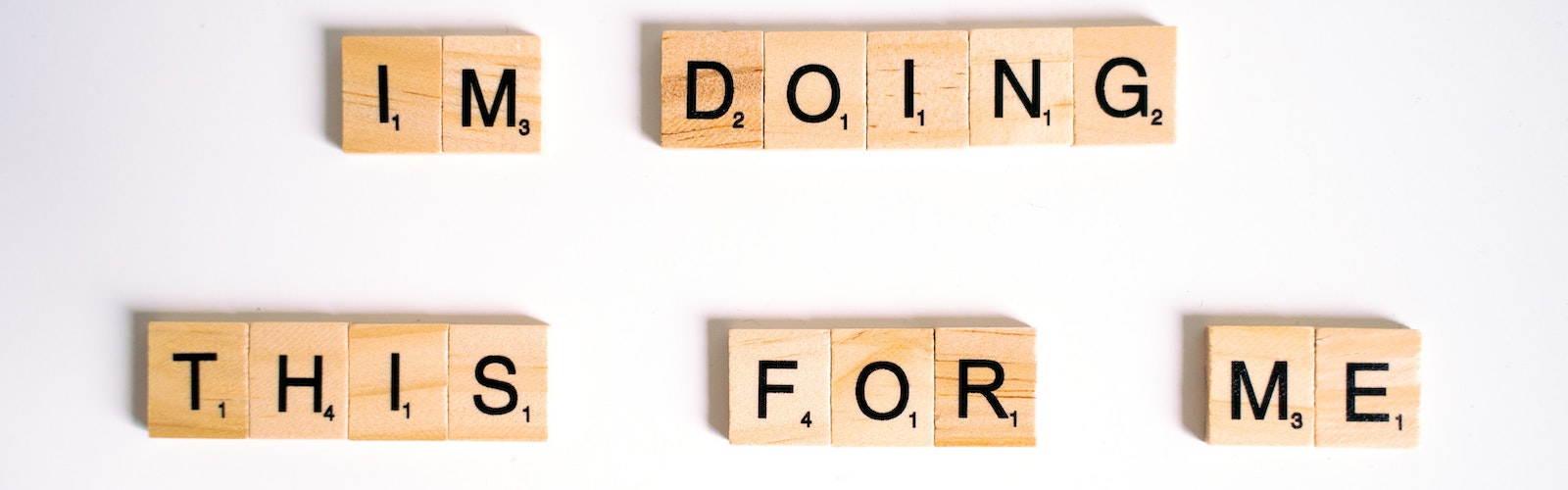 Photo of alphabet blocks arranged to make a sentence saying "IM DOING THIS FOR ME"