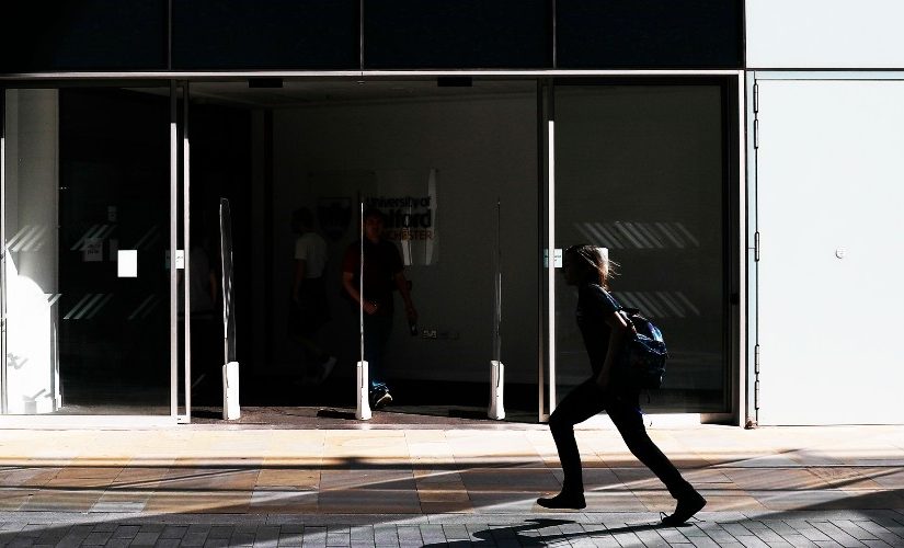 Image of the entrance to the University of Salford MCUK building, with a person walking across.