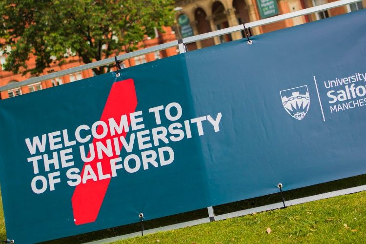 A sign outside of Campus saying "Welcome to the University of Salford."