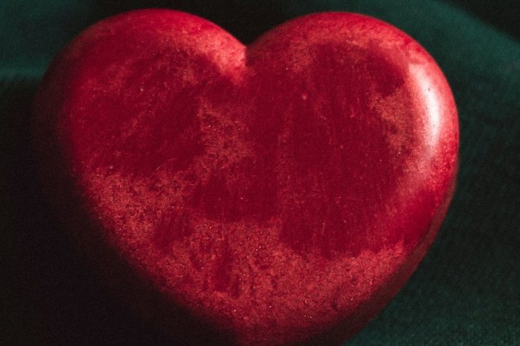 Photograph of a red stone heart on a green background