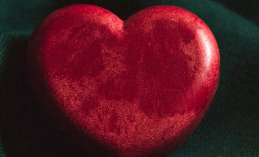 Photograph of a red stone heart on a green background