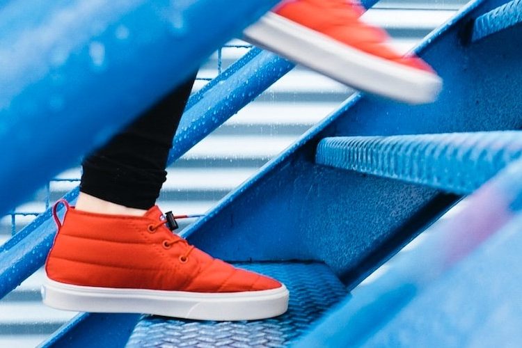 Image of a pair of feet wearing orange trainers walking up blue steps