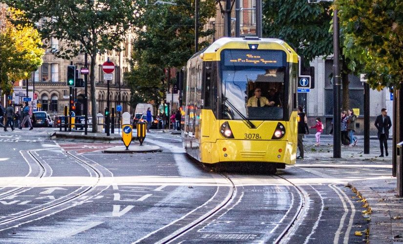 Photo of a yellow tram coming towards the camera on the tram line with people walking on the sidepaths