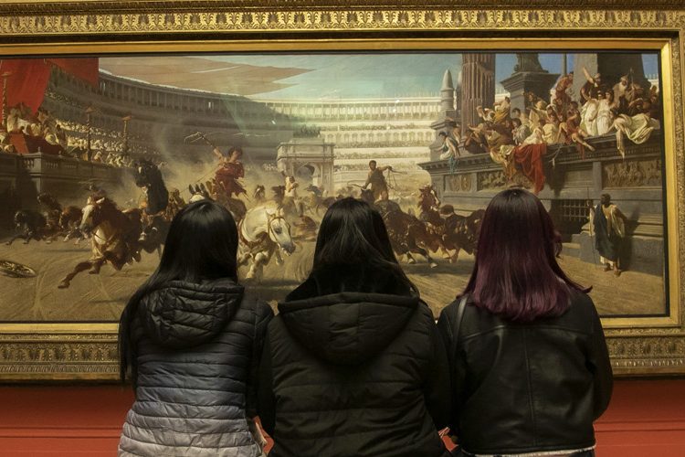 Photo of friends from the back looking at the painting inside the art gallery