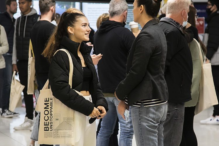 Photo of women wearing a black jacekt with a tote bag talking to counsellor wearing gray blazer