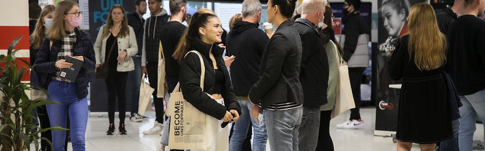 Photo of women wearing a black jacekt with a tote bag talking to counsellor wearing gray blazer