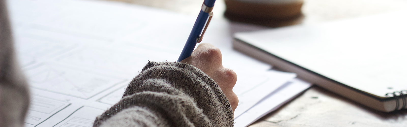 Photo of person writing on paper using a blue pen