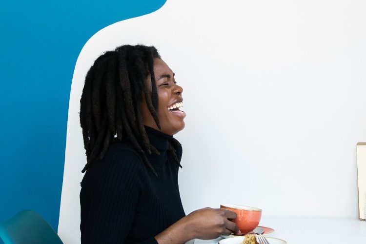 Image of a woman and man against a blue and white background drinking and laughing.