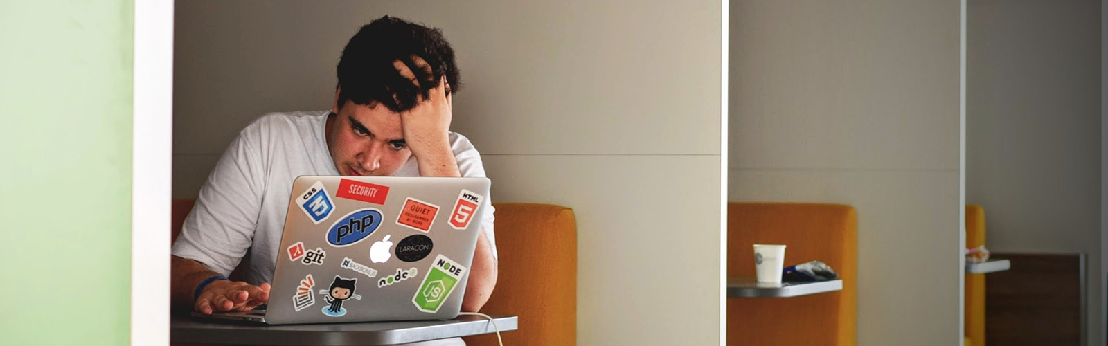 Student holding their head as they complete work on their laptop