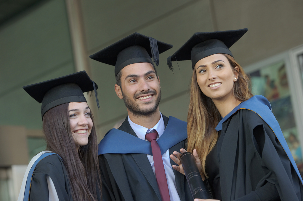 Three graduates in the gown and cap