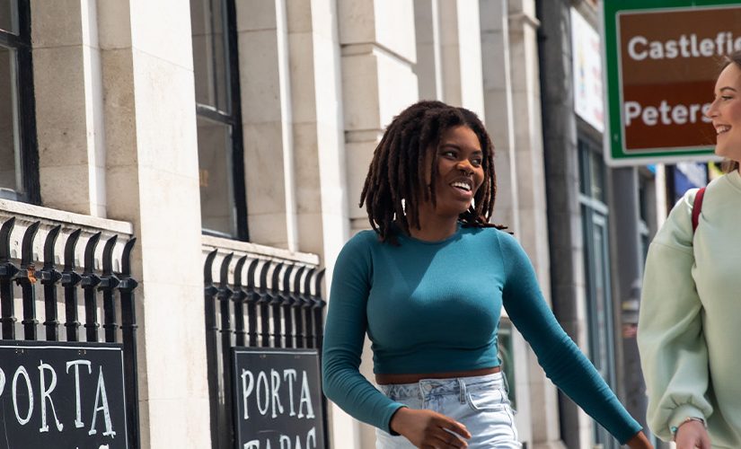 Photo of 2 girls laughing looking at each other on the sidewalk