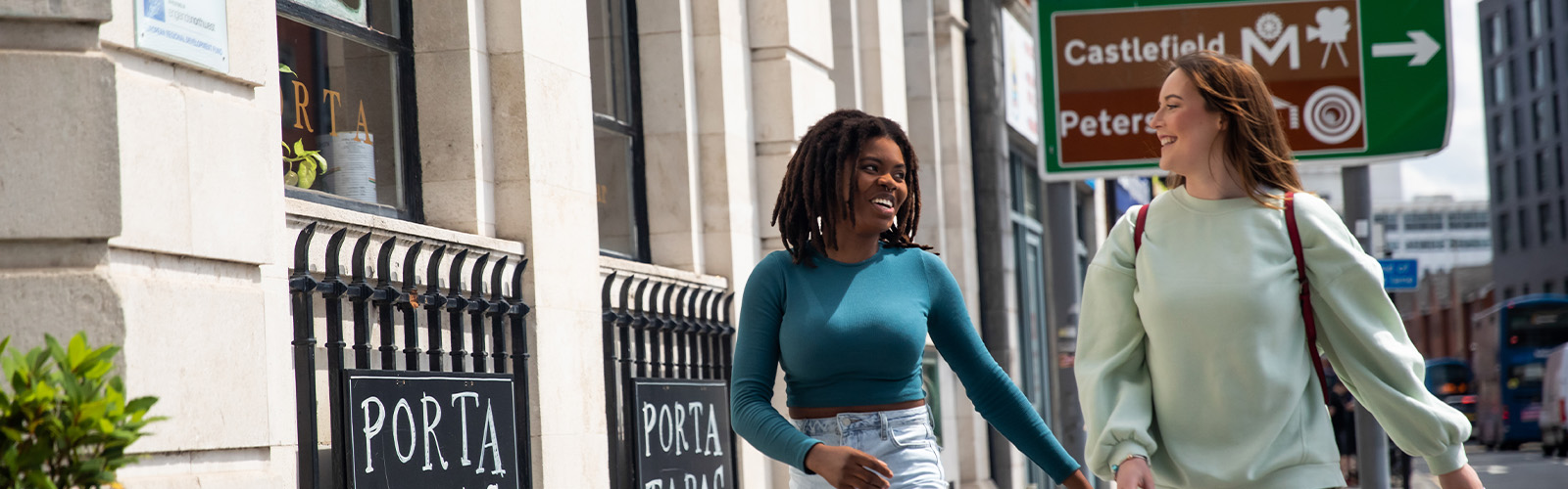 Photo of 2 girls laughing looking at each other on the sidewalk