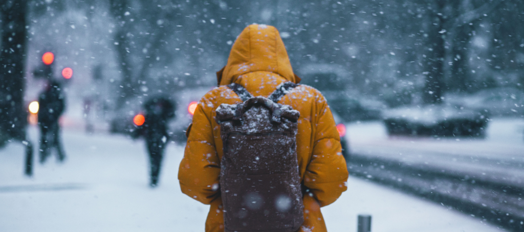 Student wearing a warm winter coat in the snow on the way to a lecture.