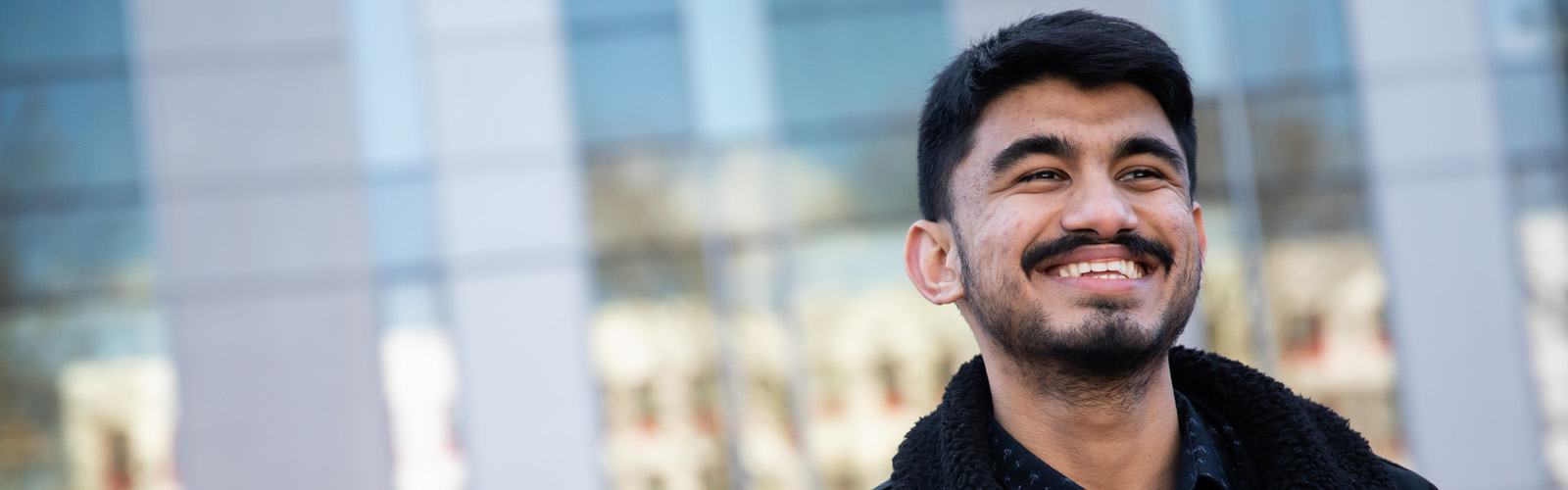 Photo of Sujan smiling outside the Chapman Building